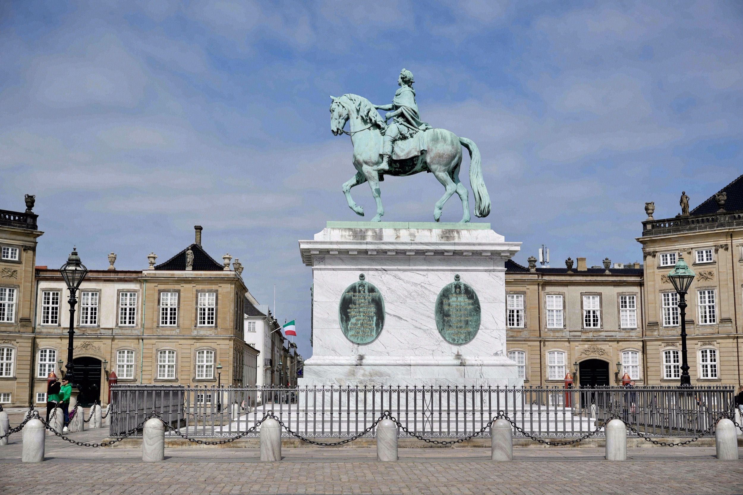 Die gruene Reiterstatue Frederiks V. auf dem Amalienborg-Schlossplatz, flankiert von zwei der vier Palaisgebaeude.