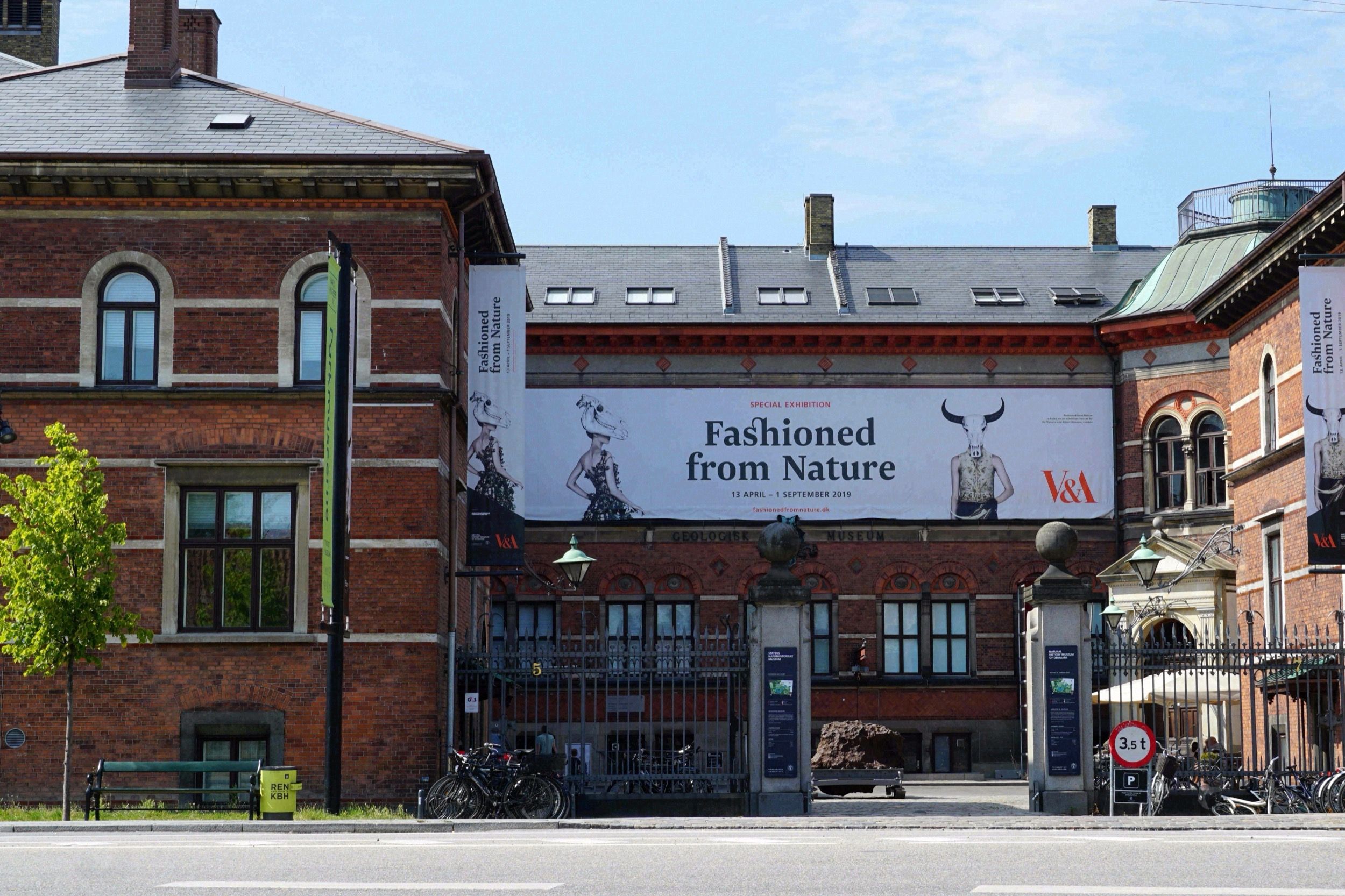 Eingang des Designmuseum Danmark aus rotem Backstein mit einem Ausstellungsbanner der V&A-Kooperation Fashioned from Nature.