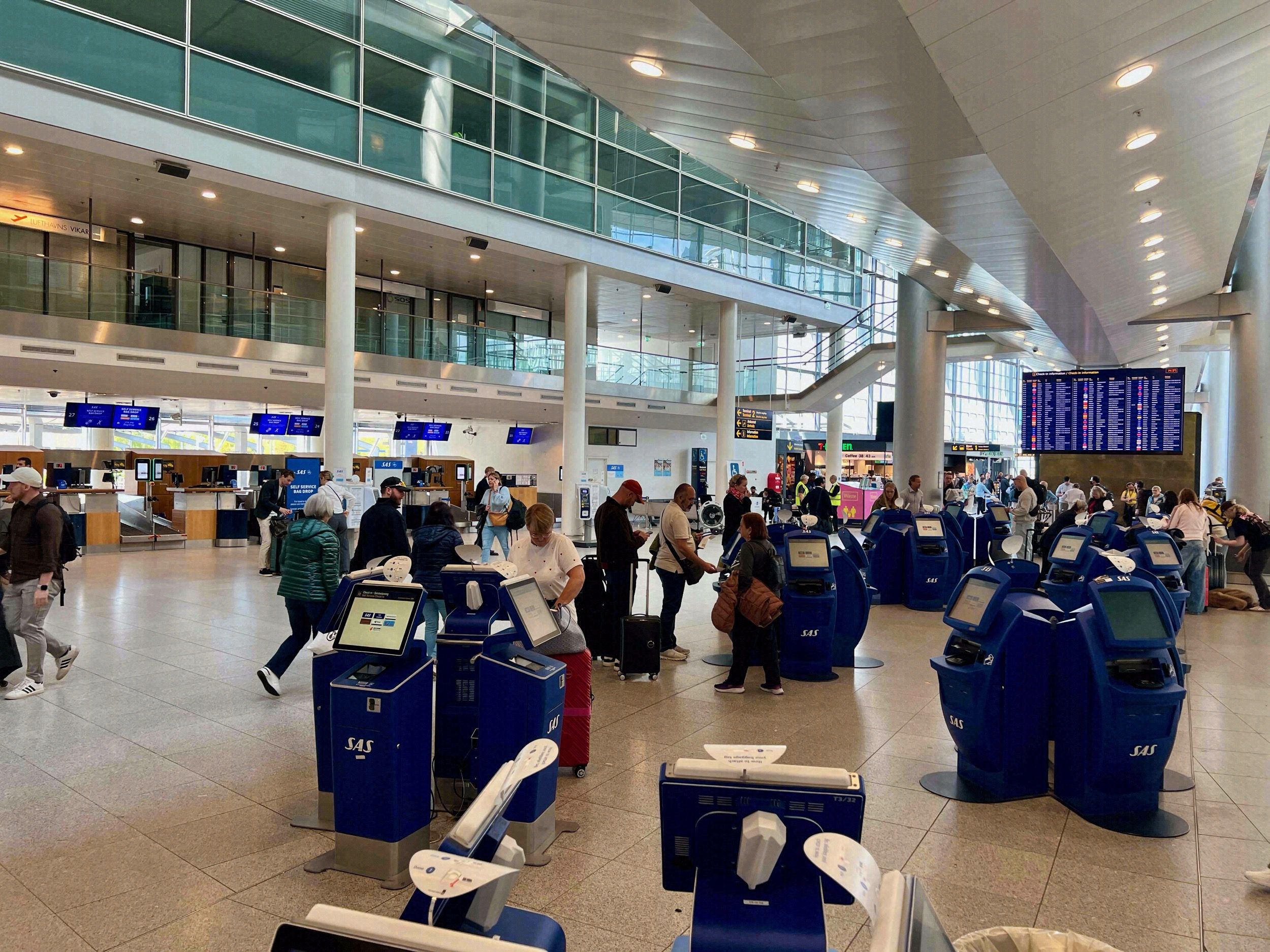 Belebte Check-in-Halle des Kopenhagener Flughafens Kastrup mit blauen SAS-Self-Service-Automaten und Reisenden.