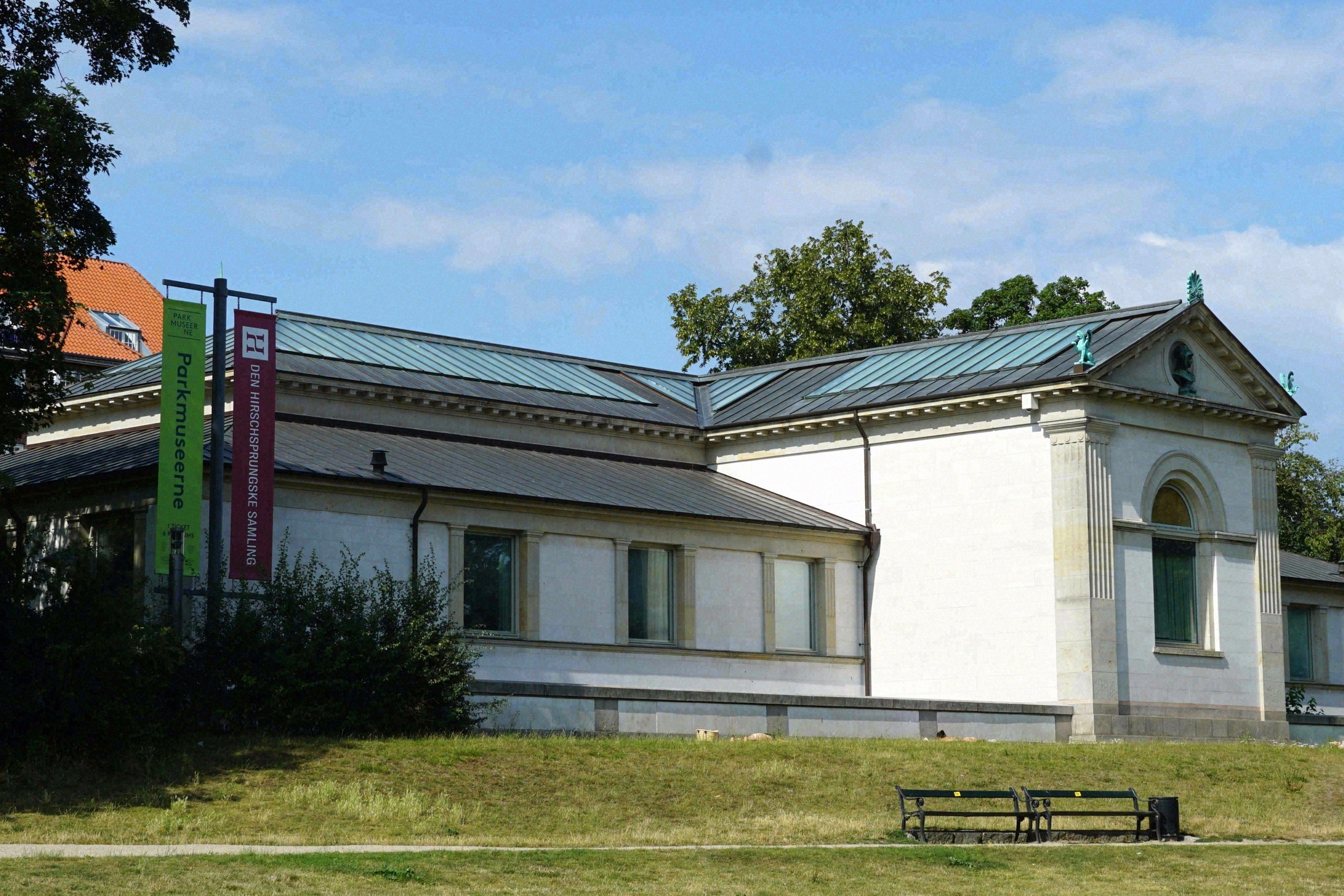Neoclassical white museum building of the Hirschsprung Collection with a Parkmuseerne banner, set in greenery.
