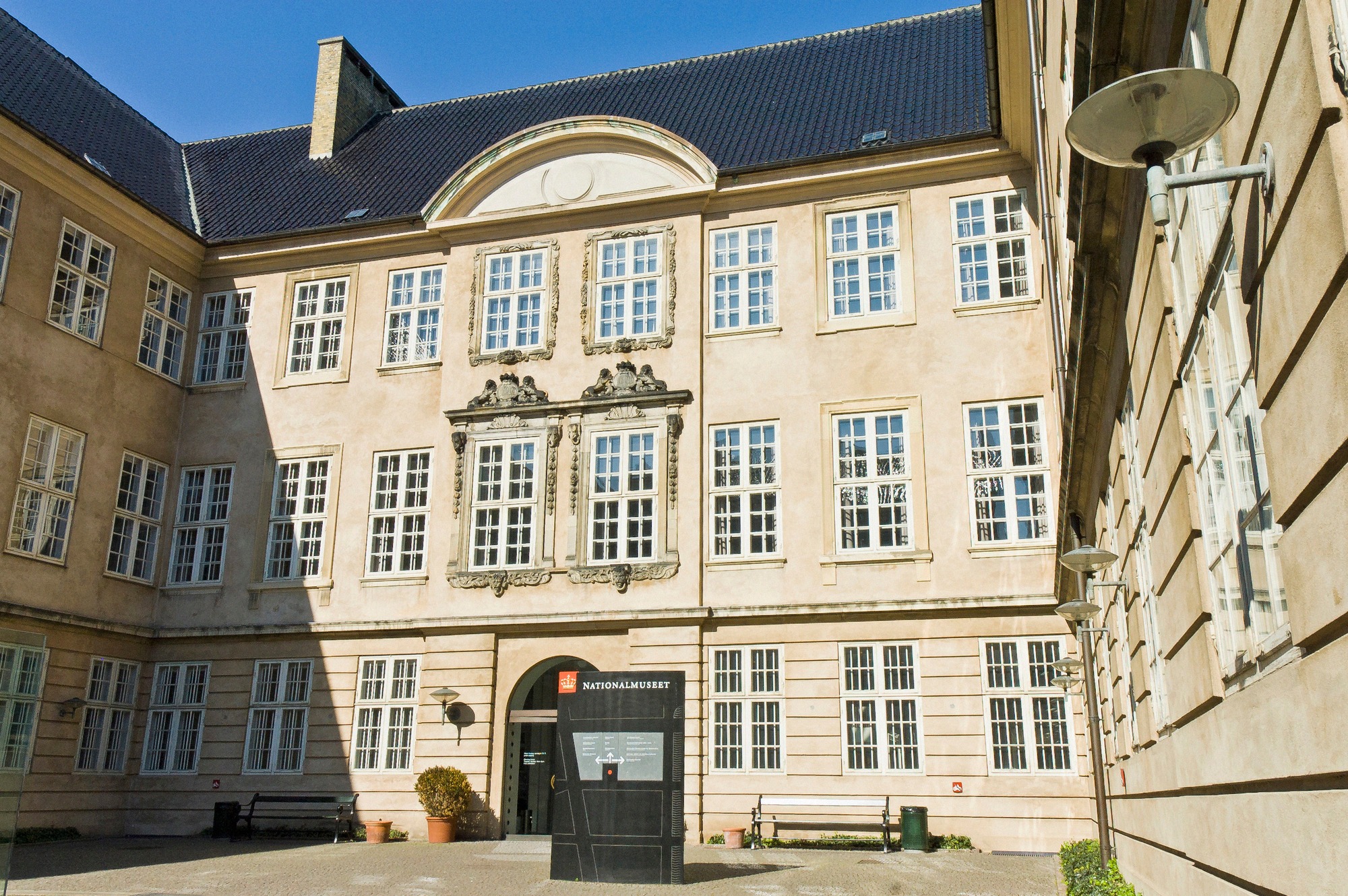 The baroque courtyard of the National Museum of Denmark in Copenhagen, with its distinctive entrance portal and the museum's sign on the pale facade.