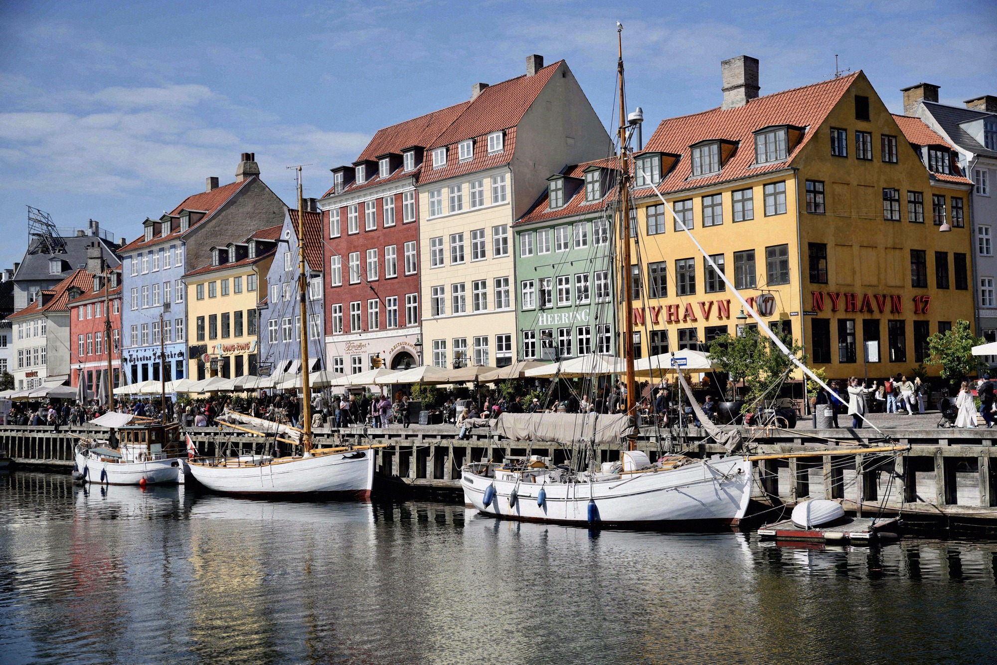 Die ikonische Hafenpromenade Nyhavn mit ihren farbenfrohen Fassaden, traditionellen Segelbooten und belebten Cafés.